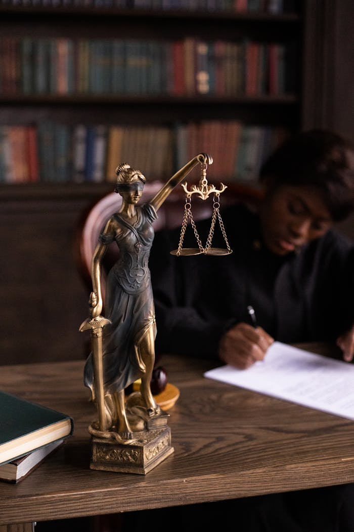 our-story Close-up of Lady Justice figurine on a lawyer's desk with books and documents.